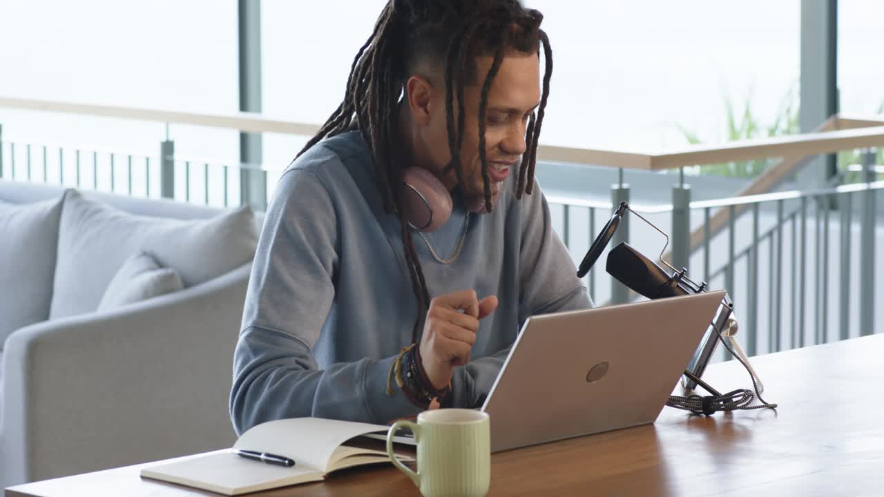 Mid adult man adjusting smartphone mount and microphone for recording typing on laptop at office