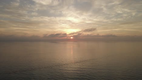 Beautiful-golden-cloudy-sunrise-on-ocean-horizon,-calm-and-peaceful