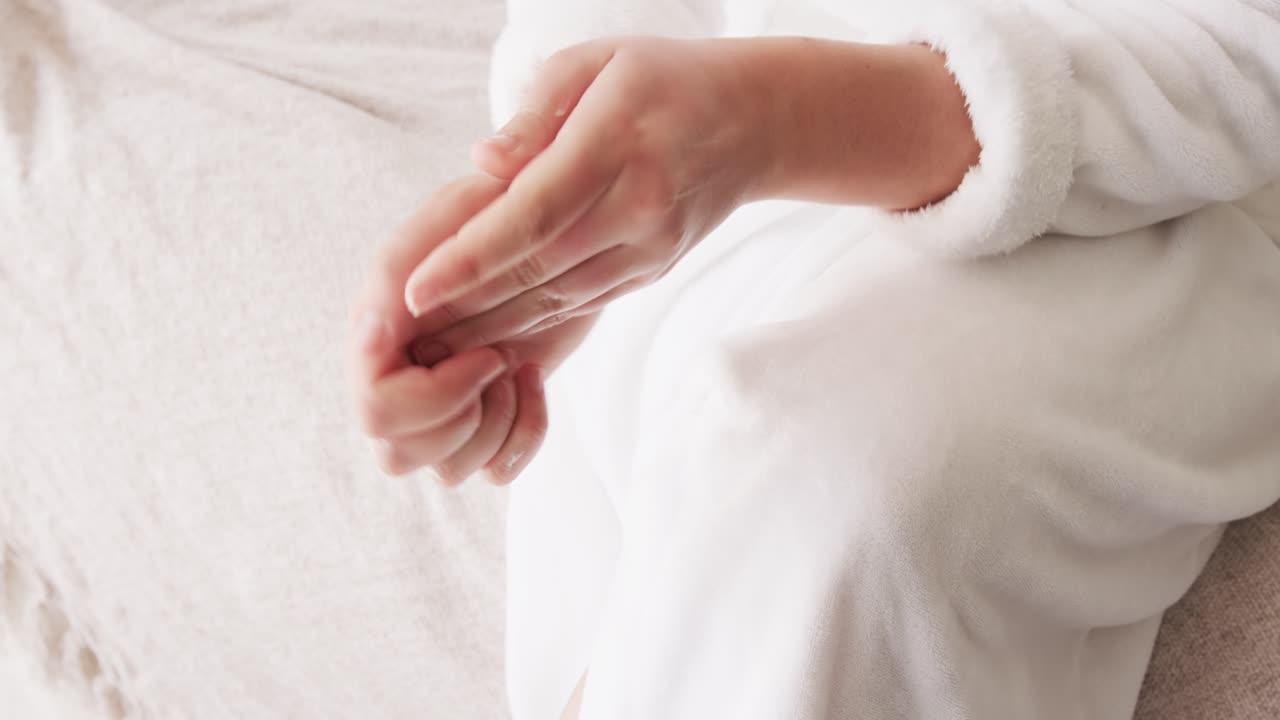 Hands are squeezing white cream tube and dispensing lotion then massaging into hands for hydration