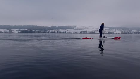 Slow-motion-footage-of-a-woman-on-a-stand-up-paddleboard-SUP-on-a-lake-in-Switzerland-in-winter
