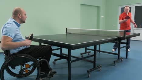 a man in a wheelchair plays ping pong. people with disabilities play table tennis. rehabilitation of the disabled. paralympic sport.