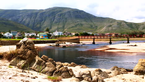 Dark tannin rich water of Kleinmond lagoon flowing under iconic red foot bridge