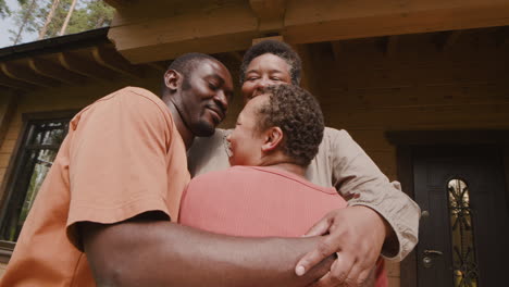 Portrait-Of-Happy-Family-Embracing-Outside-Home-In-A-Sunny-Morning