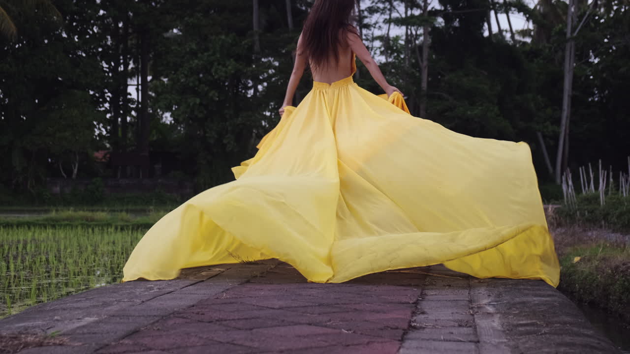 Woman in a yellow flowing dress in a rice paddy