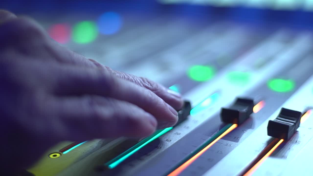 primer plano de una mano deslizando perillas en una consola de iluminación o una plataforma de dj con un movimiento de seguimiento suave