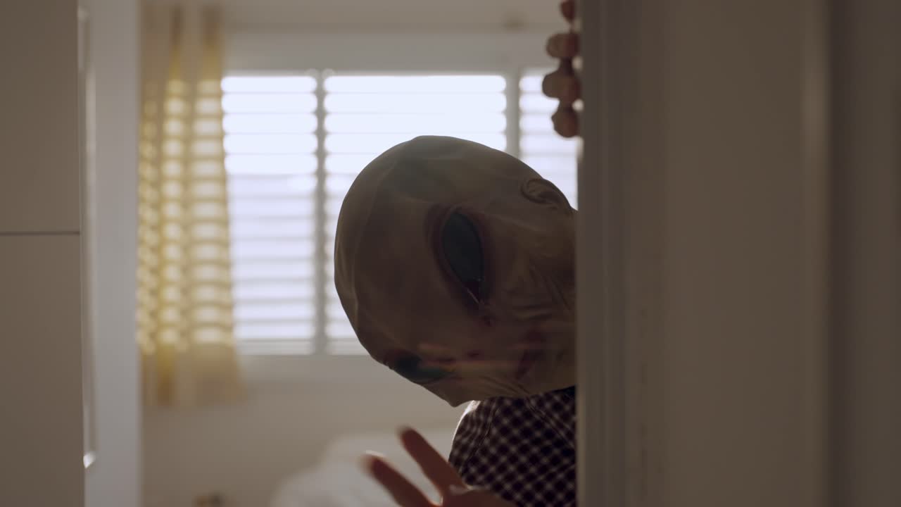 A Creepy alien peeks around a doorway inside a bright home. Surreal, horror-like atmosphere. Perfect for concepts of fear, intrusion, science fiction, Halloween, or unexpected encounters.UFO visit
