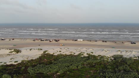 Slow-pan-right-of-the-beach,-jetty,-ocean-over-the-grass-and-dunes