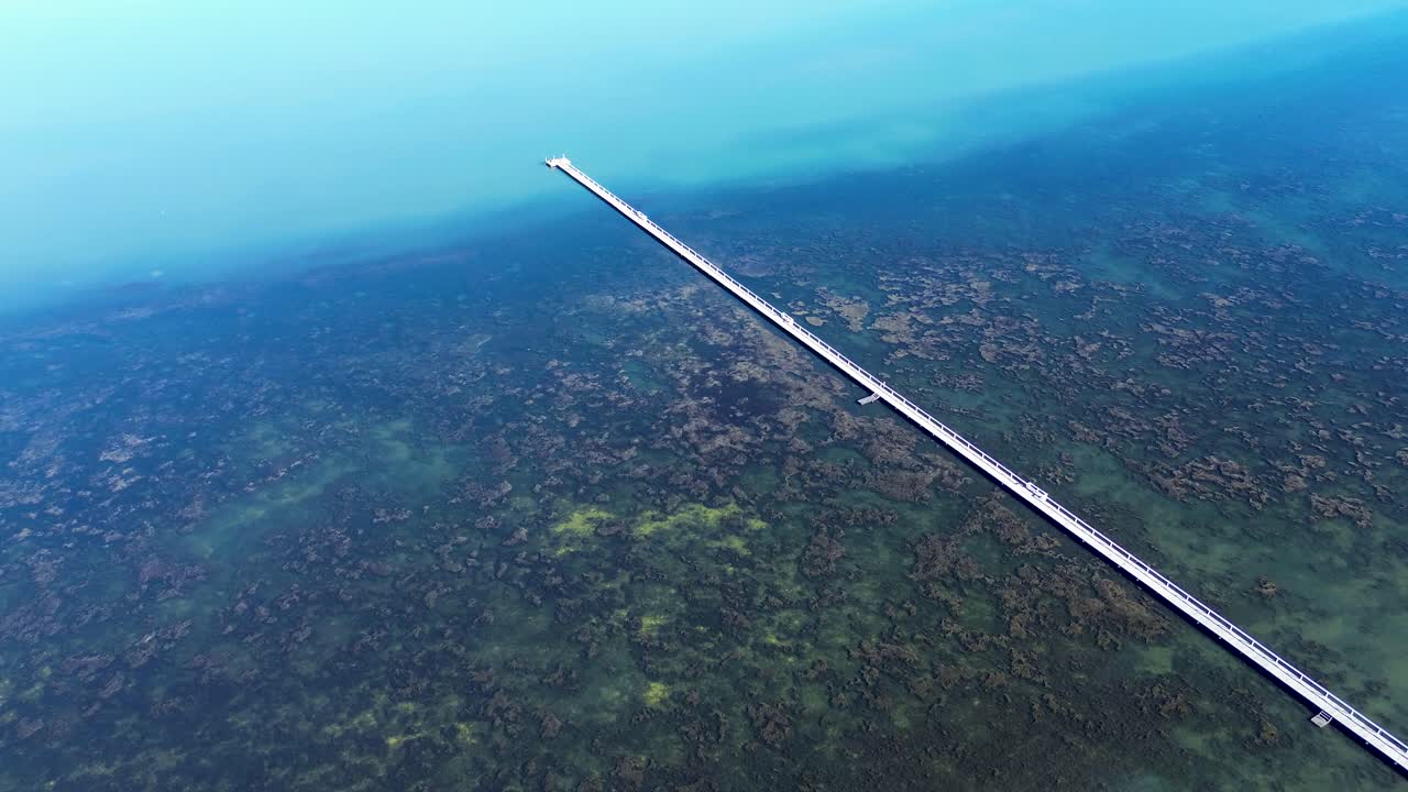 Drone aerial landscape of Long Jetty wharf fishing pier timber boardwalk in Tuggerah Lakes with seaweed sandbar in river water catchment rural outdoors Central Coast Australia peninsula travel tourism