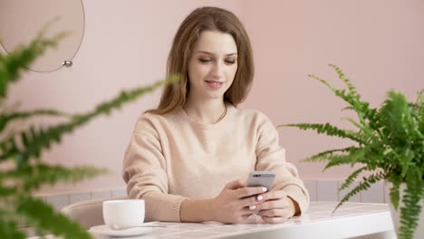 woman using smartphone in cafe drinking coffee smiling and texting on mobile phone internet, communication and technology concept 60 fps