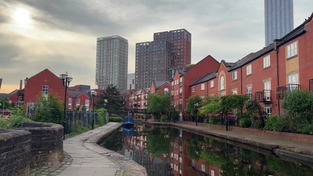 Kanalpromenade in Manchester mit roten Backsteinwohnungen und moderner Skyline.