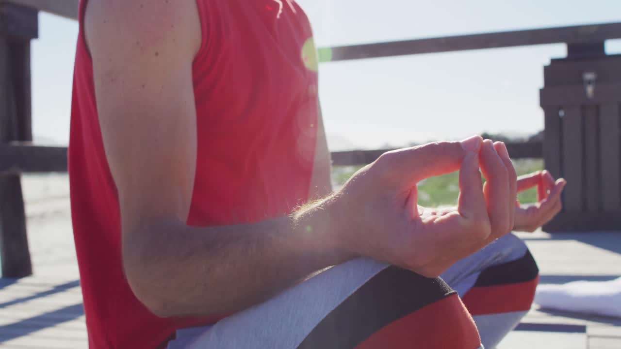 조용한 백인 남자가 해변에 앉아 요가 명상을 연습하는 비디오