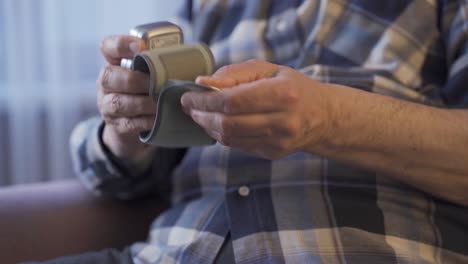 close-up old man wears sphygmomanometer on his arm.