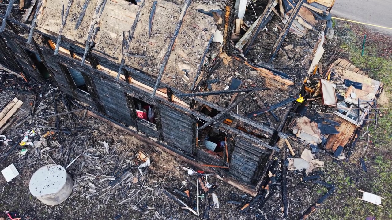 Ispezione aerea di una casa in legno distrutta dal fuoco con estesi danni strutturali