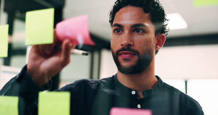 Professional Man Brainstorming with Sticky Notes on Glass Wall