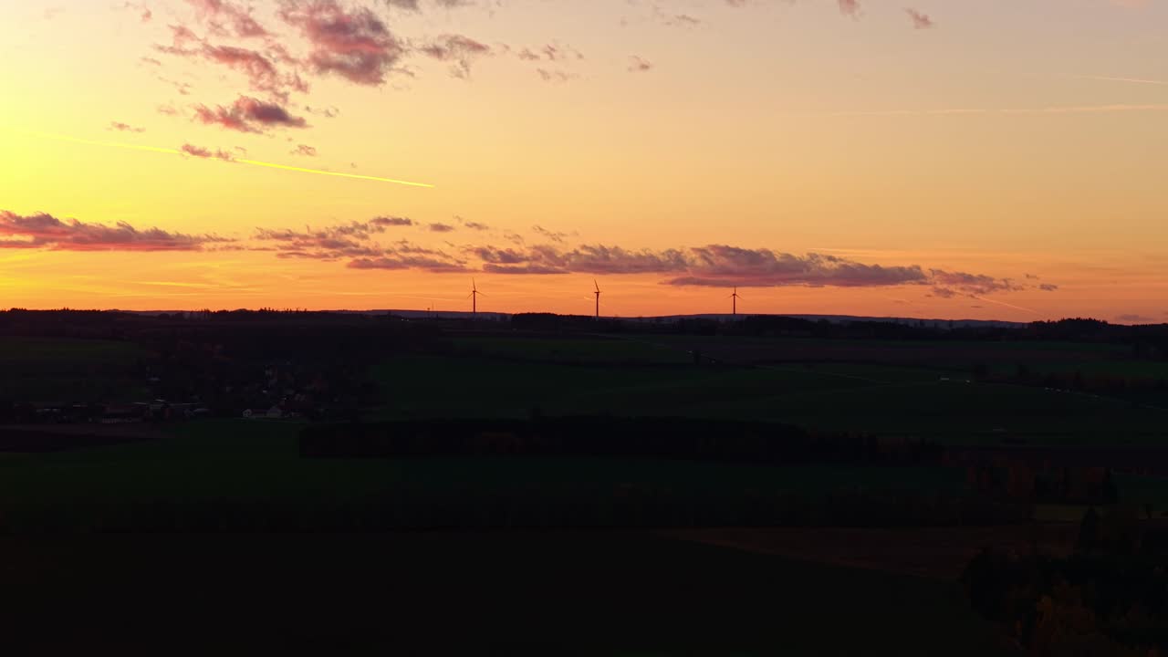 Silhouettes of wind turbines on the horizon of a golden sunset. Renewable energy in the Czech Republic region