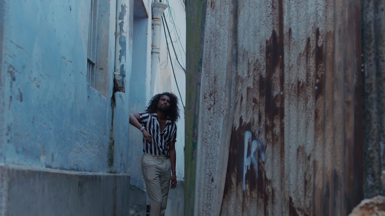 오래된 마을의 파란색 거리에서 포즈를 취하는 멋진 검은색 남성