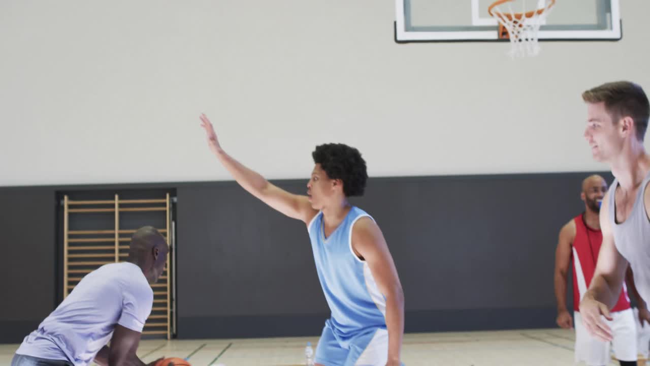diversos jugadores de baloncesto masculinos pasando la pelota y bloqueando durante el juego en la cancha cubierta, cámara lenta