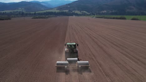 toma aérea de seguimiento del tractor aplanando un vasto campo con rodillos pesados