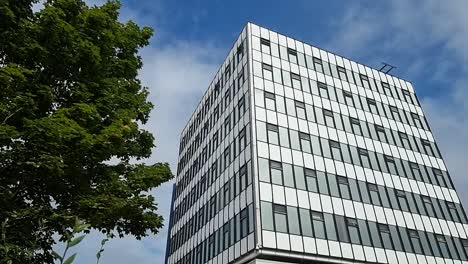 glas front modern downtown college kantoorgebouw reflecteert bewolkte blauwe hemel, pan rechts