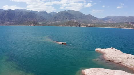 person jumping from a rock into an amazing lake at sunny day, aerial