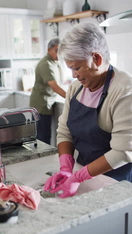 vertical video of happy senior biracial couple washing dishes