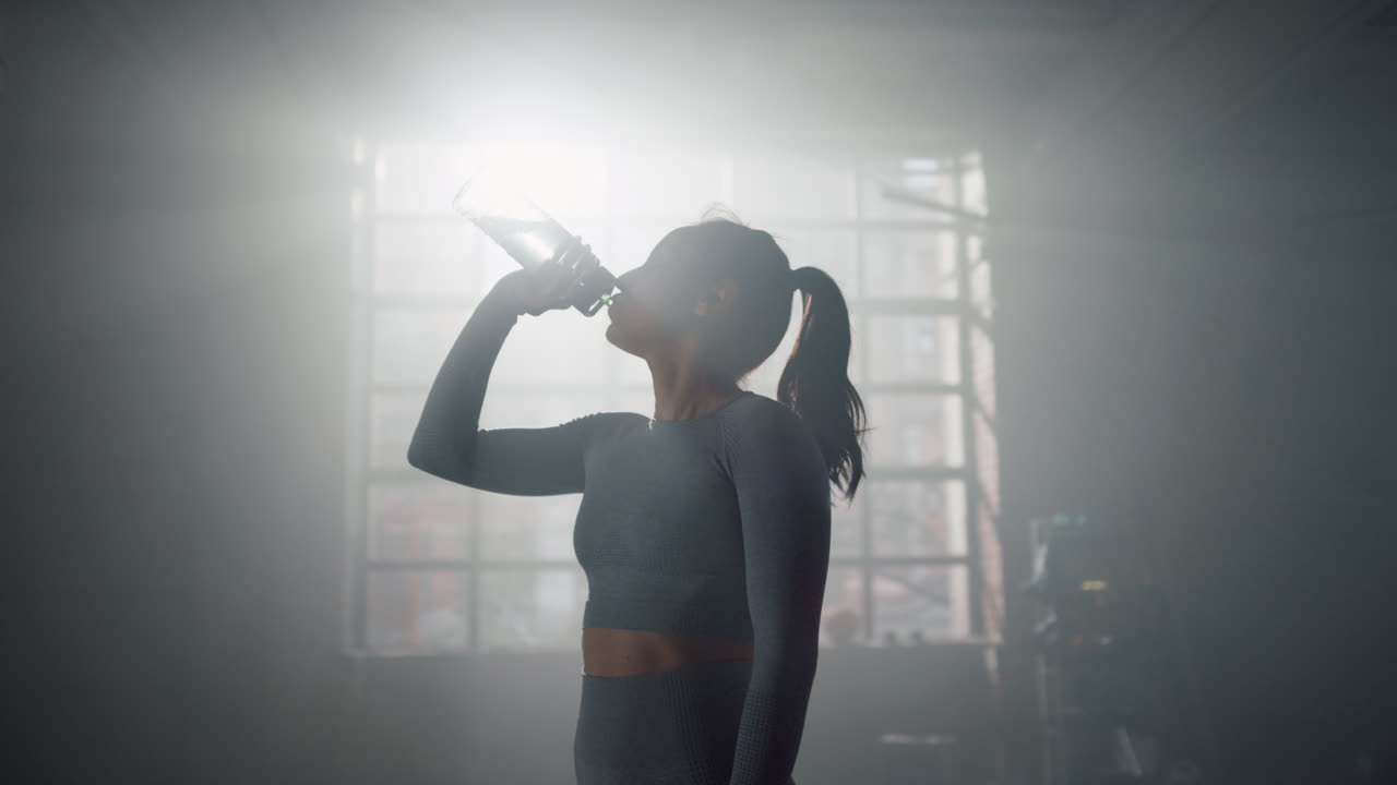 mujer bebiendo agua de una botella deportiva. culturista reabasteciendo el equilibrio de agua