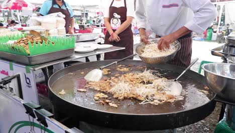 chef cooking noodles at a street market stall