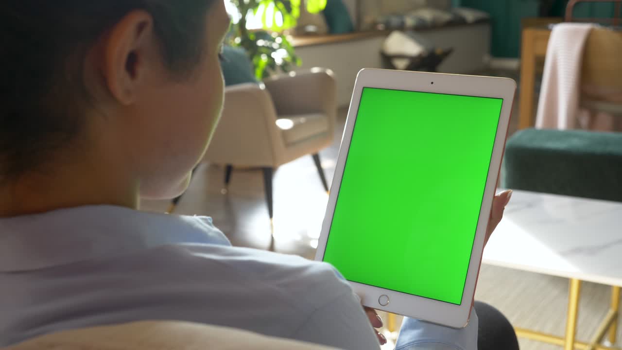 녹색 화면을 가진 디지털 태블릿을 찾는 여성, chromakey는 집에서 밝은 방에서 온라인으로 작업합니다.