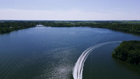 a drone flying over a speed boat boating across killarney turtle mountain lake during the summer in south west manitoba canada