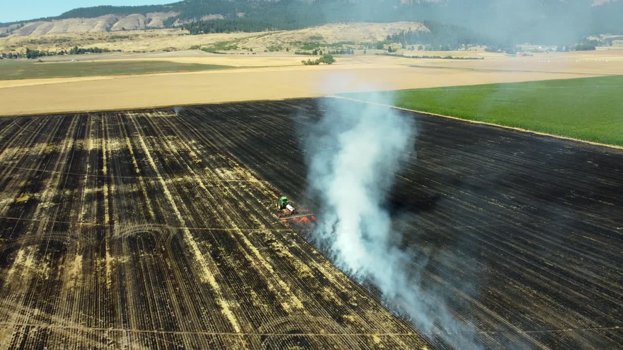US, Oregon, La Grande, 2025-08-11 - Drone view of a tractor pulling a large weed burner setting the dry plants on fire