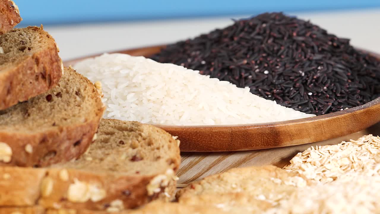 A vibrant arrangement of grains, breads, and pasta in bright lighting, showcasing diverse textures and colors