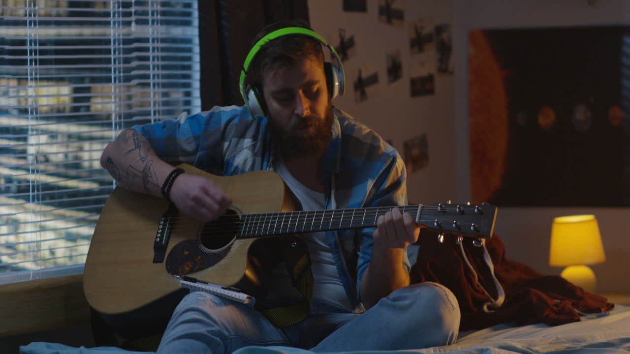 Man Playing Acoustic Guitar in Bedroom at Night