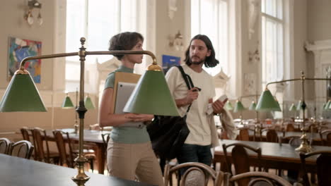 Young-students-talking-and-walking-through-library