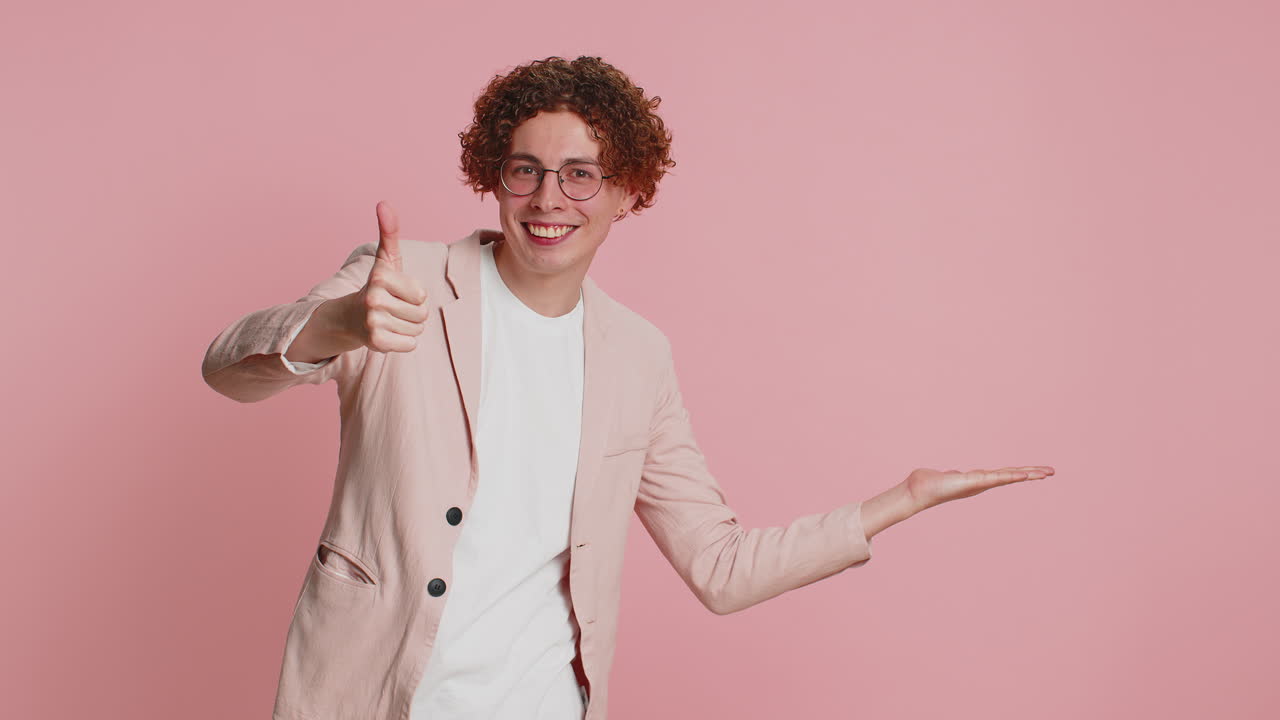 Young man showing thumbs up and pointing at right on blank space place for your advertisement logo