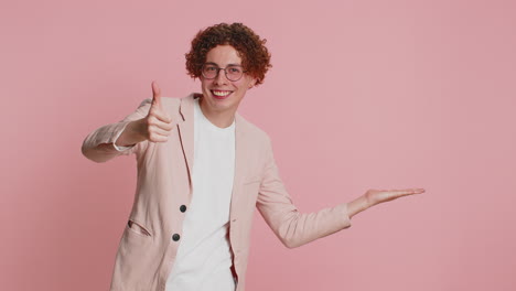 joven mostrando los pulgares hacia arriba y apuntando a la derecha en el espacio en blanco lugar para su logotipo de publicidad