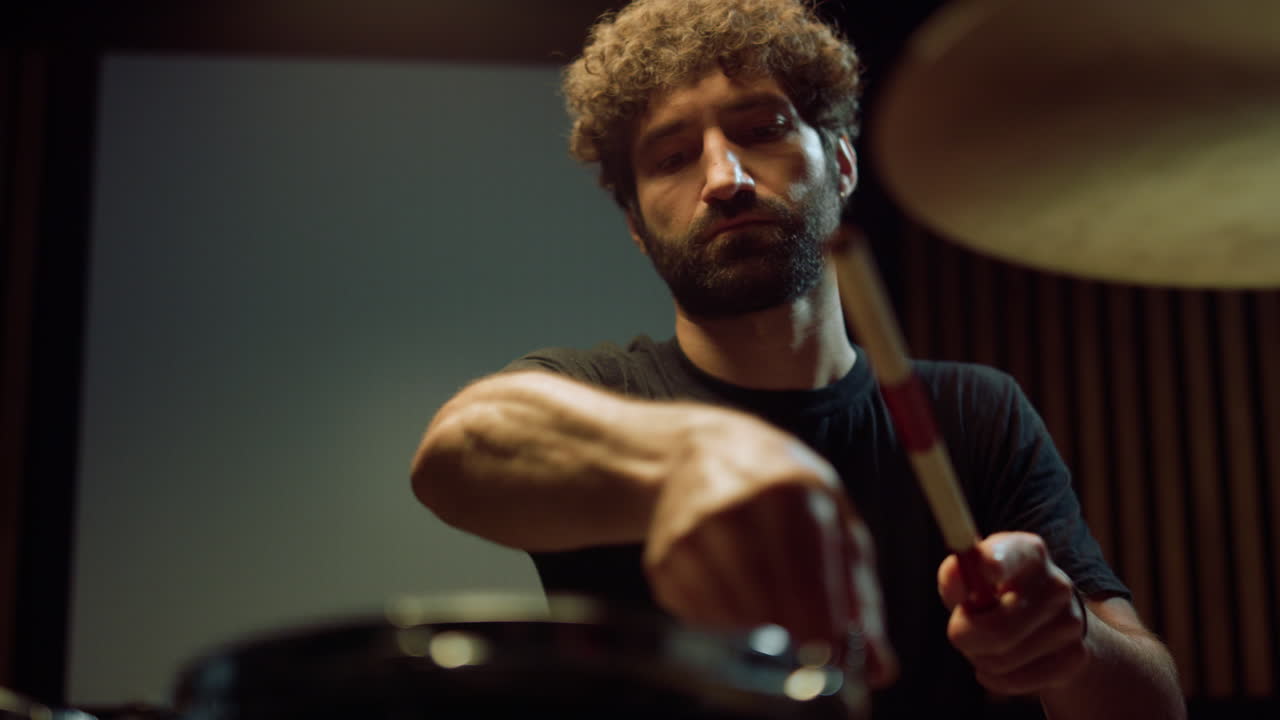 초점을 맞춘 남성 드럼 연주자 트위스팅 튜닝 키 실내