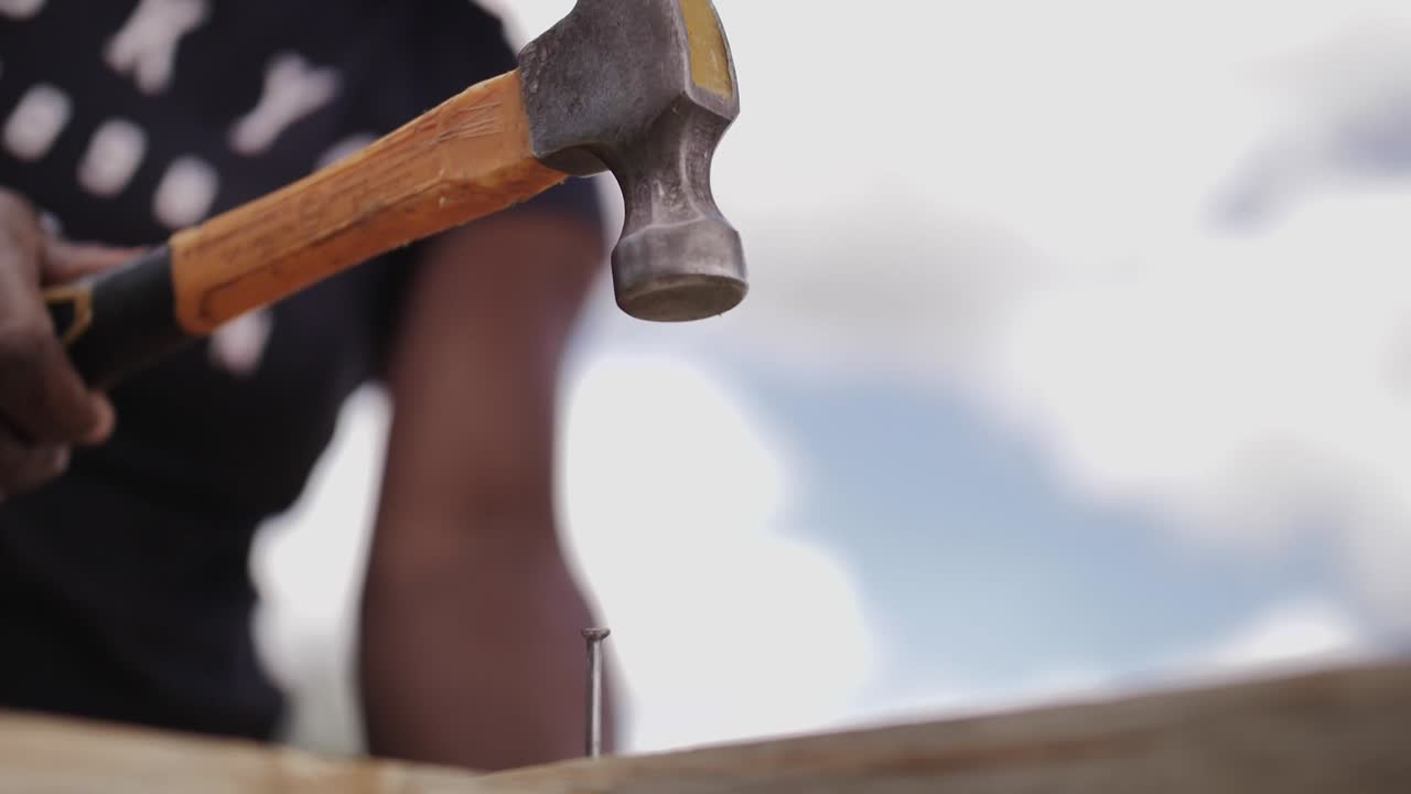 Slow motion African lady hammering a nail into furniture