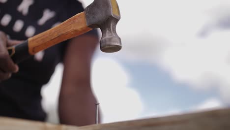 mujer africana en cámara lenta martillando un clavo en los muebles