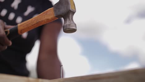 slow motion african lady hammering a nail into furniture