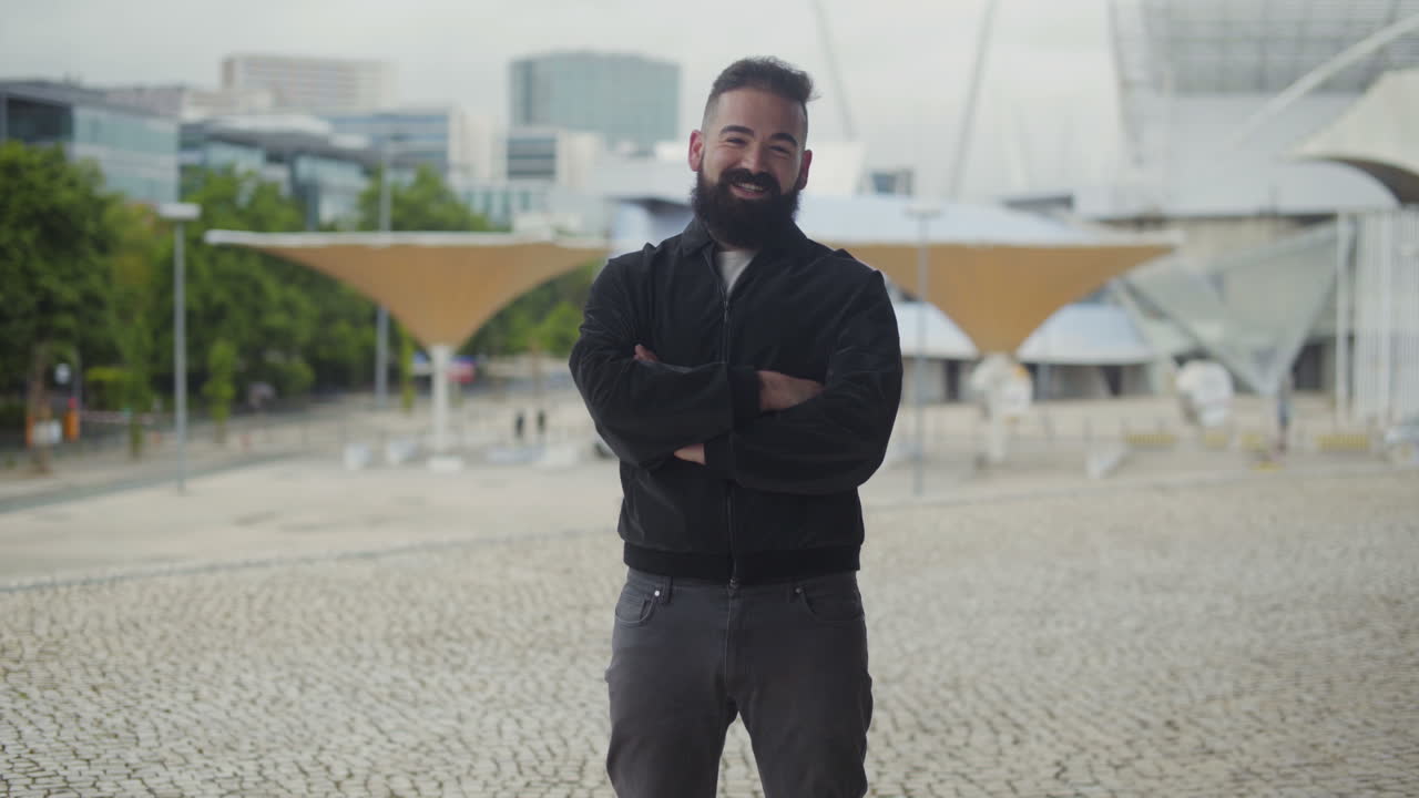 un joven barbudo confiado sonriendo y hablando a la cámara.