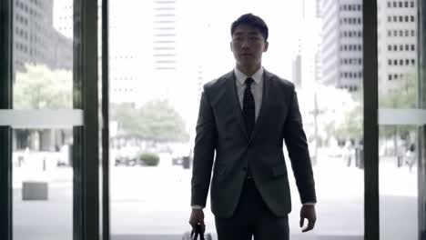 a confident professional strides purposefully through the entrance of a modern office building, showcasing determination and focus in an urban business environment.