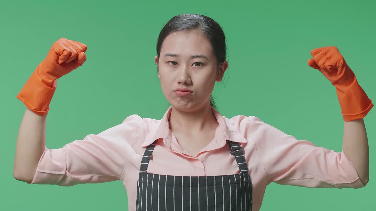 녹색 스크린 스튜디오에 서 있는 동안 그녀의 비셉스를 보여주는 아프론을 입은 아시아 여성 집주인의 클로즈업