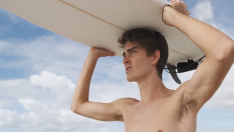 Young-man-on-beach-with-surfboard