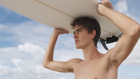 young man on beach with surfboard