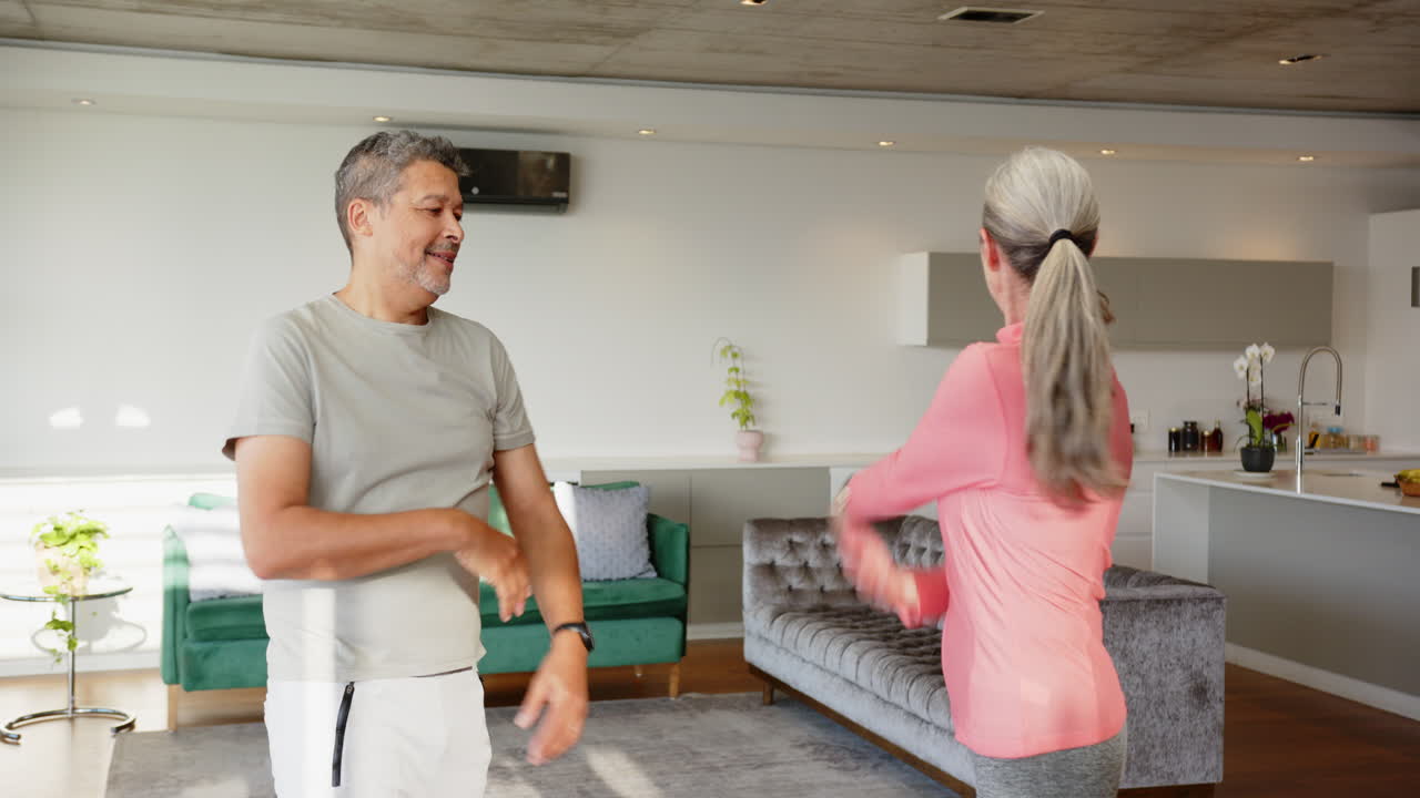 Stretching together, multiracial senior couple enjoying fitness routine at home living room