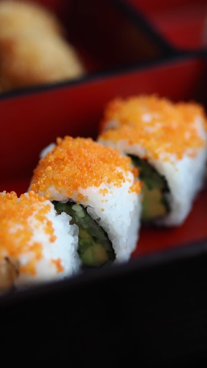 Primo piano di freschi roll di sushi California con tobiko in una bento box