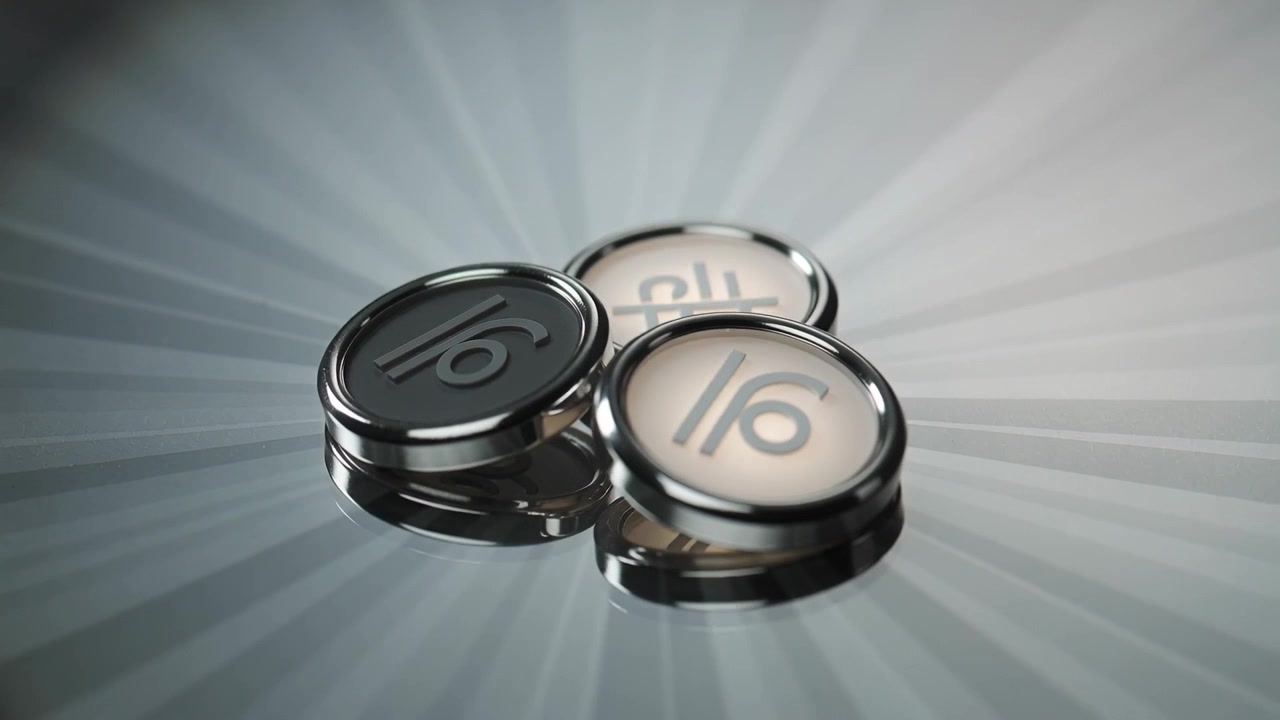 Tre roterende metaltokens, der vipper på en børstet radial overflade, lys der fejer henover og afslører 16-logoet