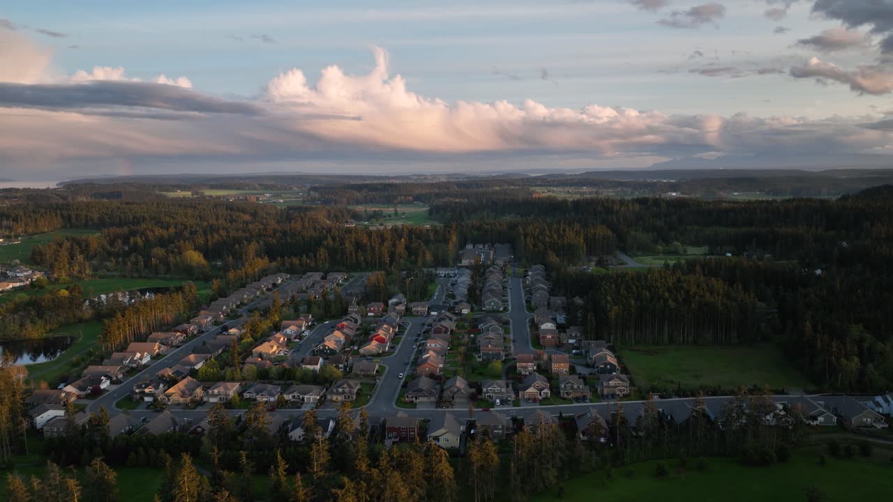Vidvinkel etableringsbilde av et amerikansk boligområde omgitt av skog og skyet himmel ved solnedgang