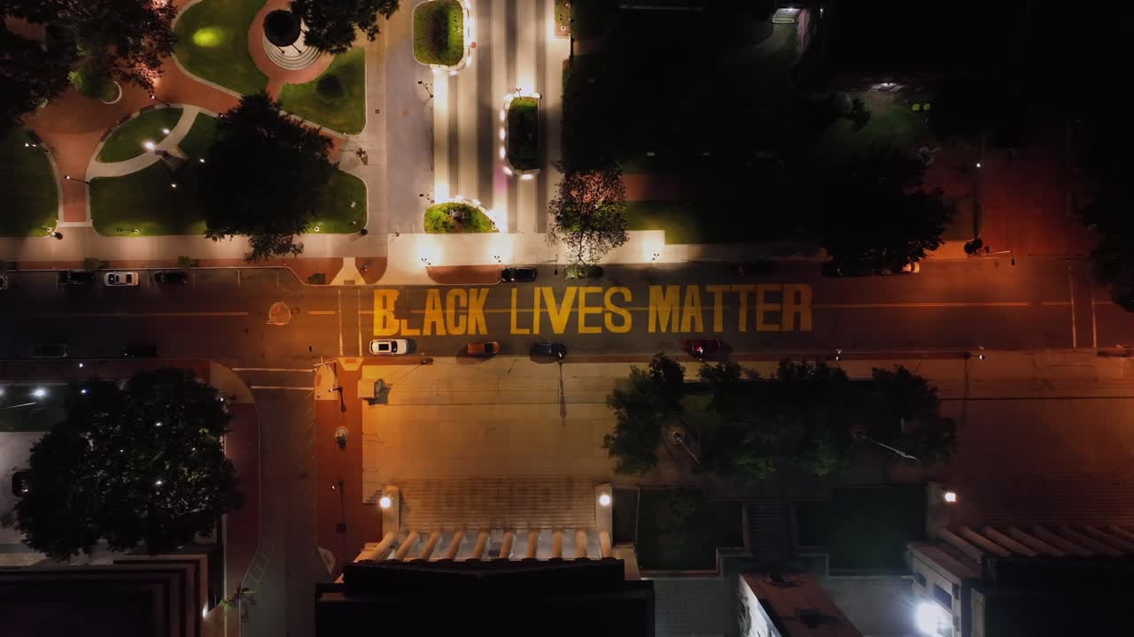 Black Lives Matter sign on asphalt street of American town. Aerial top down shot. Park with lights and lantern in city. Cozy atmosphere in USA