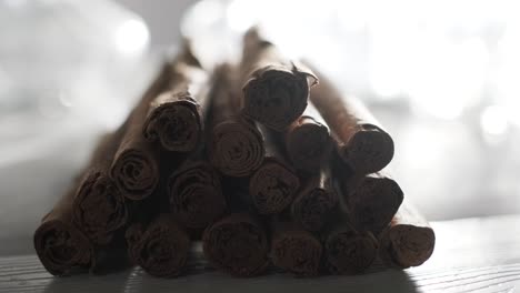 Bright-spot-light-illuminating-Cinnamon-sticks-pile-dim-down,-Close-up-shot